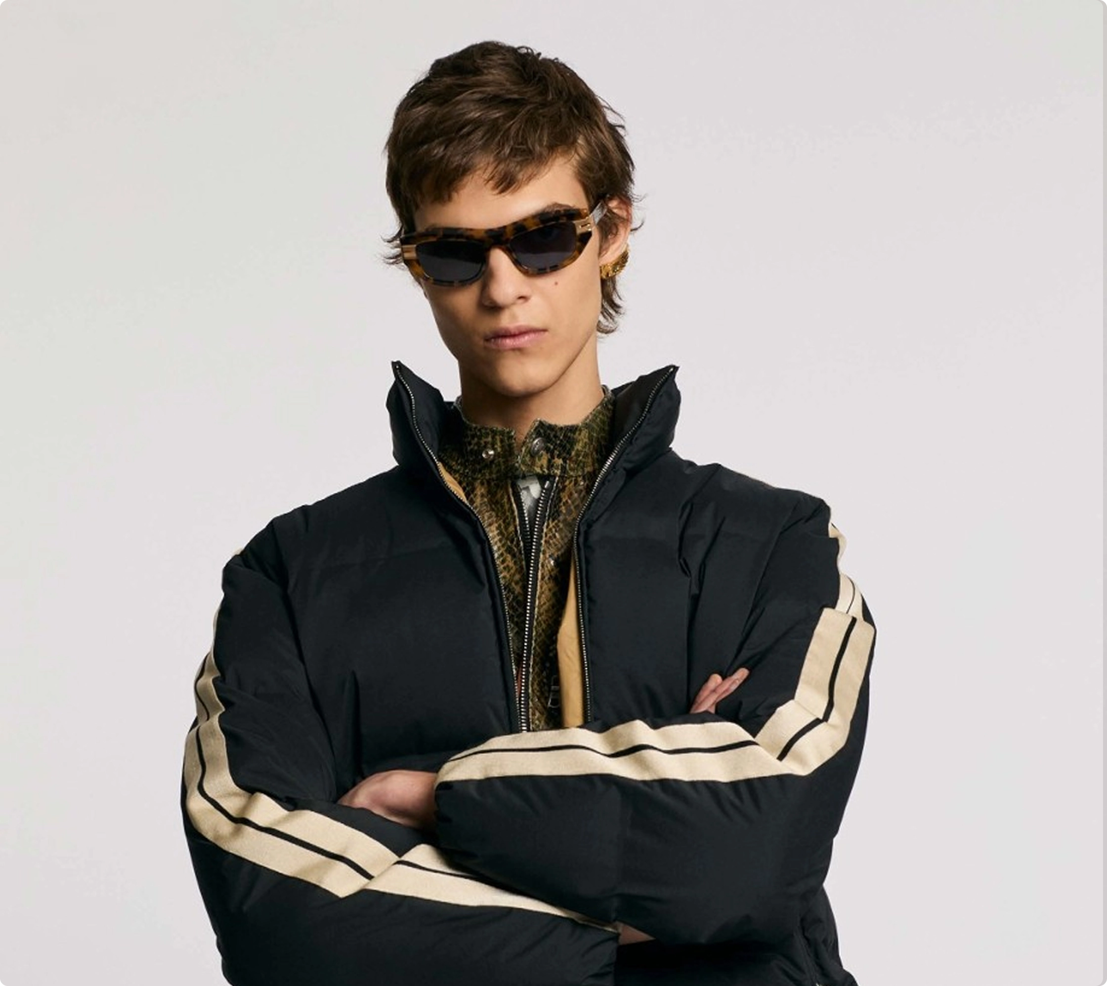 Cool person in sunglasses wearing a stylish black jacket with stripe details, arms crossed confidently.