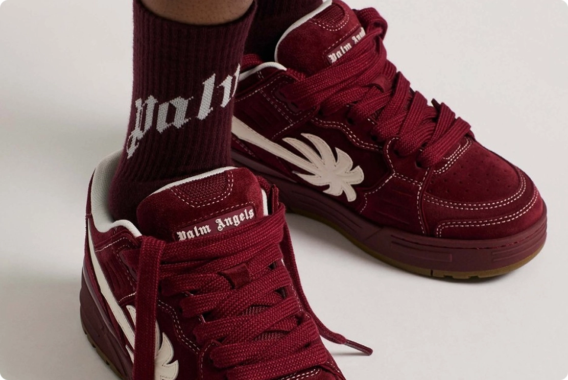 Maroon sneakers with white leaf design and matching socks featuring logo detail, showcasing stylish footwear.